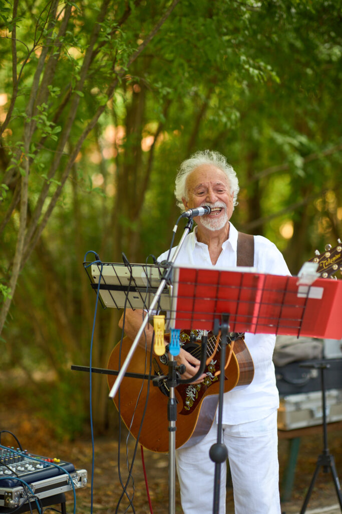 Uomo anziano canta con chitarra in un parco