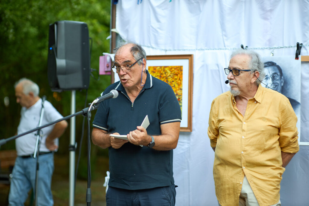 Due uomini parlano a un microfono in un evento all'aperto