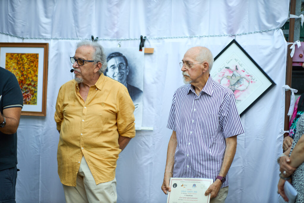 Due uomini in mostra artistica con opere in sfondo